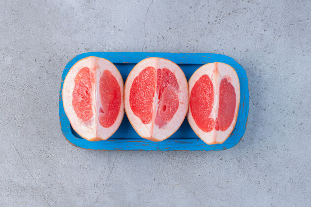 健康葡萄柚片放在大理石背景的蓝色小盘上水果美味新鲜