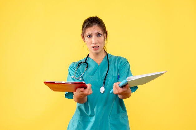 医疗前视图穿着医用衬衫的女医生拿着黄色背景的笔记黄色正面人