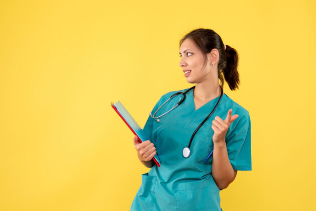 健康正面图黄色背景下穿着医用衬衫的女医生拿着分析医生医疗听诊器