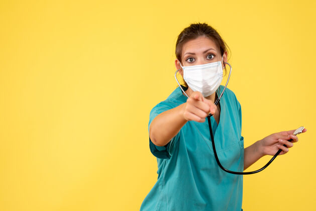 黄色正面图黄色背景上穿着医用衬衫和带听诊器面罩的女医生健康衬衫呼吸装置