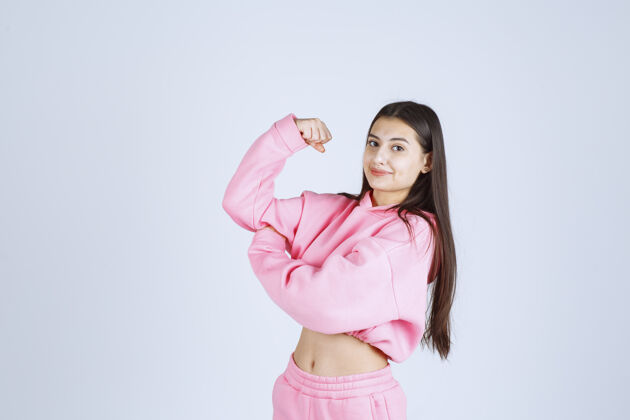 人穿着粉色睡衣的女孩展示她的拳头 感觉很强大成人人体模特工人