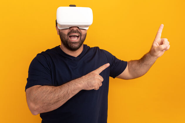 现实一个留着大胡子的男人穿着海军t恤 戴着一副虚拟现实的眼镜 用食指指着站在橙色墙上的一边目录人虚拟