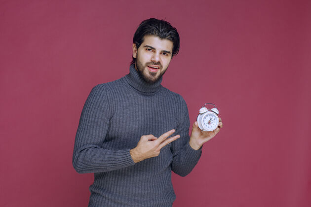 促销一个男人拿着一个白色闹钟 指着一个最好的报价服装人体模型照片