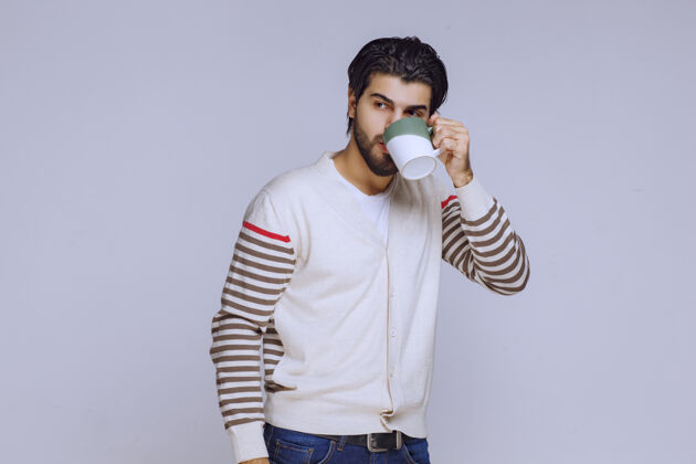 促销穿着白衬衫的男人拿着咖啡杯 喝着咖啡 感觉精力充沛热温暖人体模特