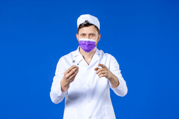 医院男医生的前视图 穿着医疗服 戴着蓝色的注射和疫苗面罩大流行注射病毒