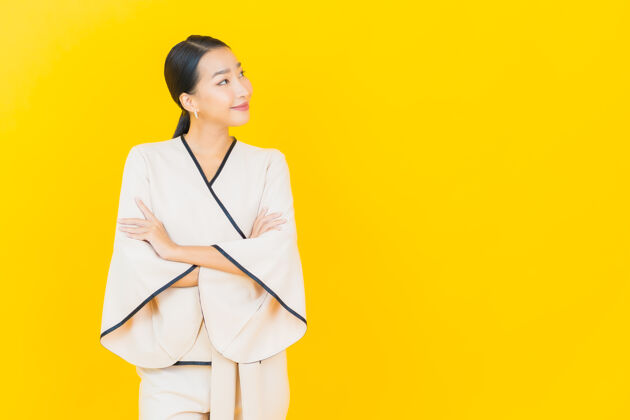 肖像美丽的亚洲年轻商业女性在黄色墙上穿着白色西装微笑的画像年轻工人成人