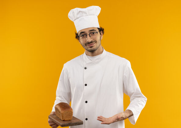 拿着年轻的男厨师身穿厨师制服 手持眼镜 用手指着切板上的面包男眼镜点