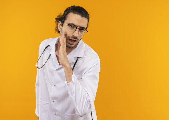 年轻戴着医用眼镜 穿着医用长袍 带着听诊器的年轻医生低声说医疗耳语医生