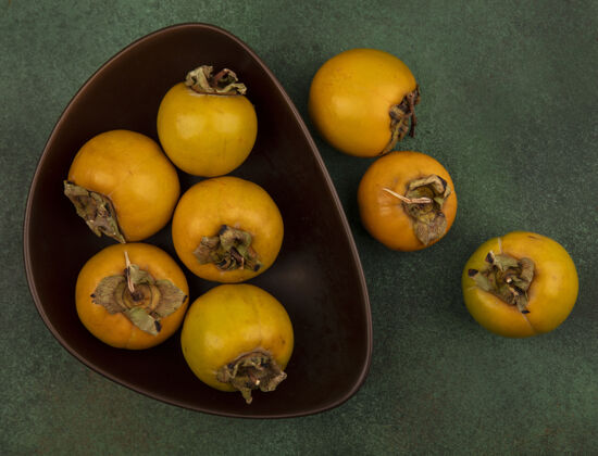 秋季顶视图充满营养的柿子水果在一个绿色的表面碗配料碗美味