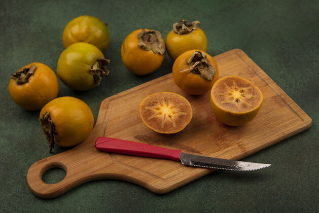 饮食顶视图的一半柿子水果在一个木制的菜板与整个柿子水果隔离在绿色的表面刀配料秋天柿子