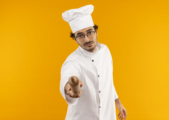 年轻年轻的男厨师穿着厨师制服 戴着眼镜 手里拿着擀面杖制服男厨师