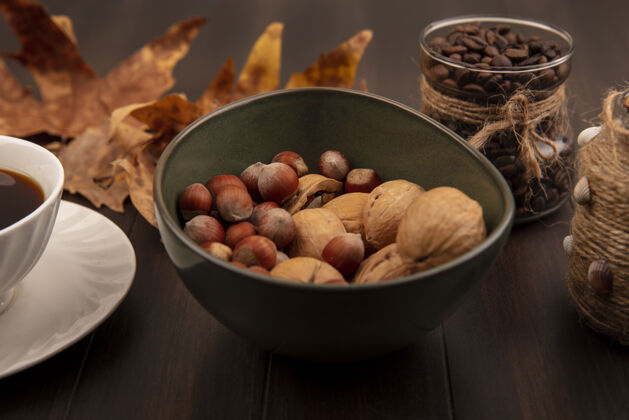 木材顶视图坚果在一个碗上与咖啡豆在一个玻璃罐上与一杯咖啡在一个木制的表面种子配料咖啡