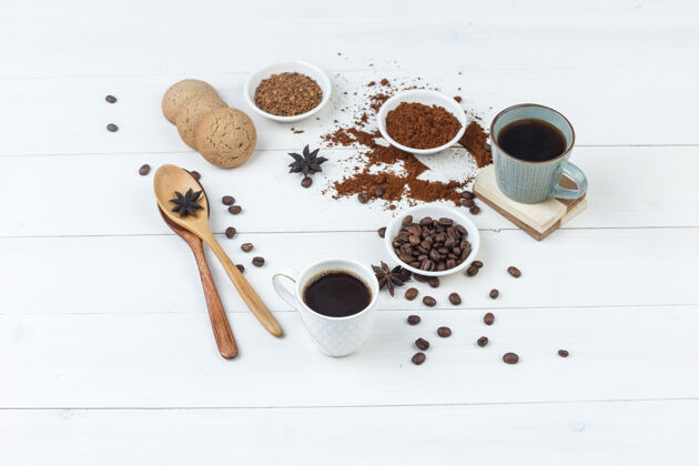 研磨一套咖啡豆 磨碎的咖啡 香料 饼干 木制勺子和咖啡杯在木制背景上高角度视图质地曲奇拿铁