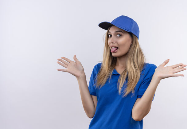 交货年轻的女送货员穿着蓝色制服 戴着帽子 露出舌头 摊开双手帽子舌头年轻