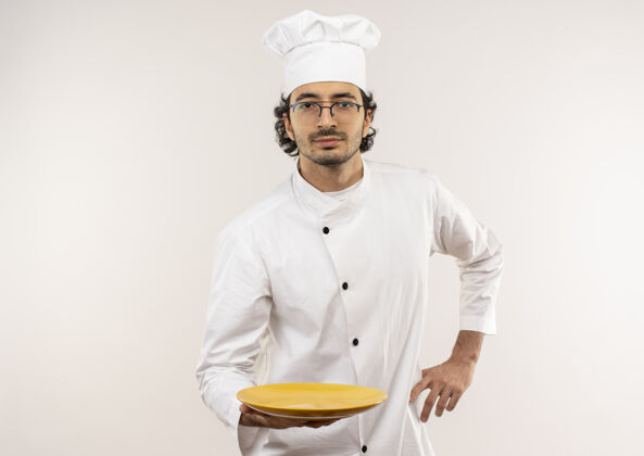 臀部年轻的男厨师穿着厨师制服 戴着眼镜拿着盘子 手放在臀部制服厨师盘子