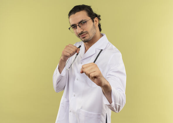 光学年轻的男医生戴着眼镜 身穿白色长袍 手持听诊器 站成战斗姿势眼镜绿色男人