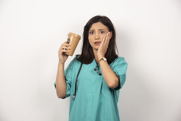 保健女医生拿着一杯咖啡托着白底的脸颊听诊器工人杯子