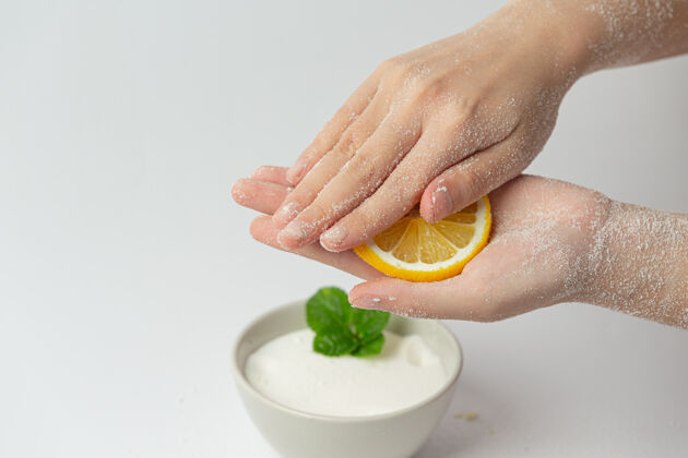 剥皮年轻女子用天然柠檬磨砂膏擦手上的白色表面皮肤涂抹护理