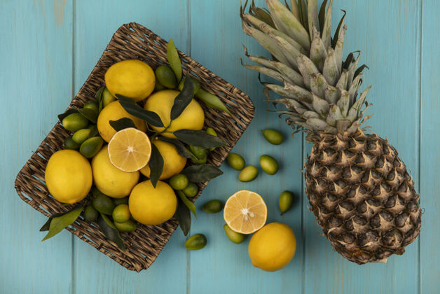 配料新鲜水果的俯视图 如金盏花和柠檬放在柳条托盘上 菠萝被隔离在蓝色的木制表面上柠檬美味水果
