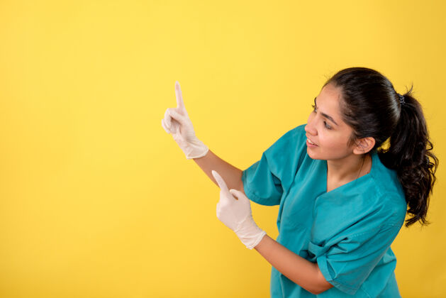 乳胶前视图微笑的女医生 戴着乳胶手套 手指指向黄色背景手套手指正面
