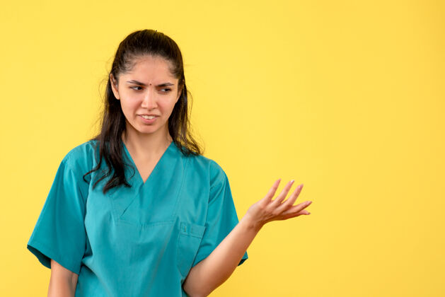 成人前视图困惑的女医生穿着制服站在黄色背景上前面商业职业