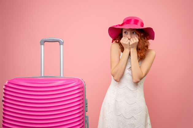 帽子年轻的女性游客与粉红色的帽子和粉红色的墙壁上的包的正面视图美丽快乐夏天