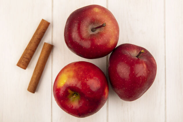 美味顶视图新鲜的红色苹果与肉桂棒隔离在一个白色的木制表面等级配料近距离