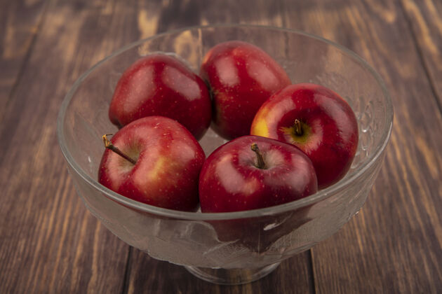 美味新鲜的红苹果在木制表面上的透明水果碗俯视图清晰农业美味