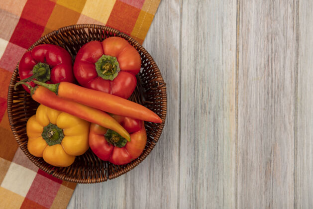 饮食彩色甜椒的顶视图在一个格子布桶上的灰色木制表面与复制空间胡椒美味木材