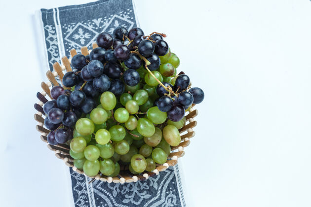 角新鲜的葡萄放在一个篮子里 背景是白色的厨房毛巾高角度视角成熟叶子厨房