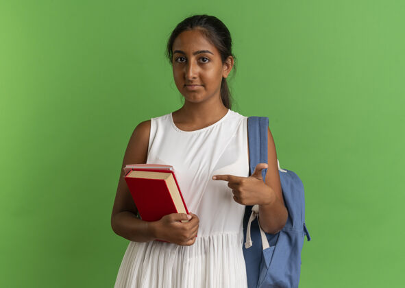 笔记本年轻的女学生背着书包拿着笔记本指着书绿色学生女学生