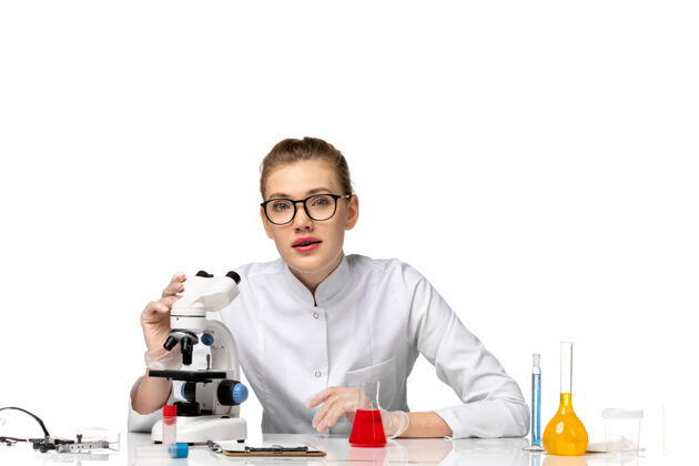 笔记本电脑前视图穿着白色医疗服的女医生在白色空间使用显微镜处理解决方案使用病毒医疗