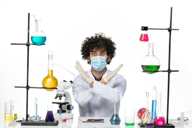 实验室前视图男性化学家穿着医疗服 戴着面罩 坐在一个空白处 摆出不同的解决方案实验室男性化学家医学