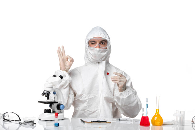 医疗正面图：男医生穿着防护服 戴着面罩 因为白色空间上有一个装着柯维德的瓶子套装疾病到期