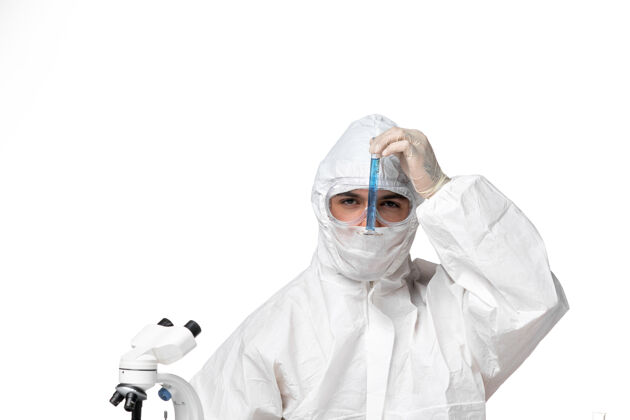 医生正面图：男医生穿着防护服 戴着面罩 因为covid拿着蓝色溶液的烧瓶 在空白处到期面罩正面
