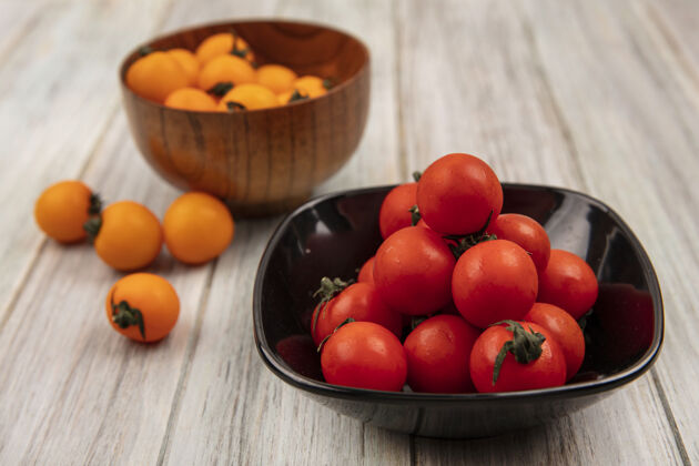 农业黑色碗上的软红色西红柿顶视图 灰色木制表面上的木制碗上有橙色西红柿软有机配料