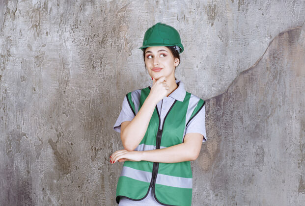 工作场所身着绿色制服 头戴安全帽的女工程师看上去既困惑又体贴模特人体模型不确定