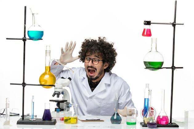 科学正面图身着医疗服的男性化学家正坐在桌子前 白色桌子上摆着溶液只是专业坐着