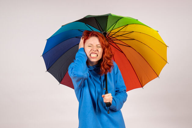 阳伞白色墙壁上带着彩色伞的年轻女性的正视图情绪伞庇护所