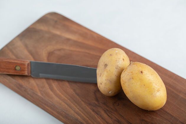 新新鲜的有机土豆和刀放在棕色木板上有机团体集