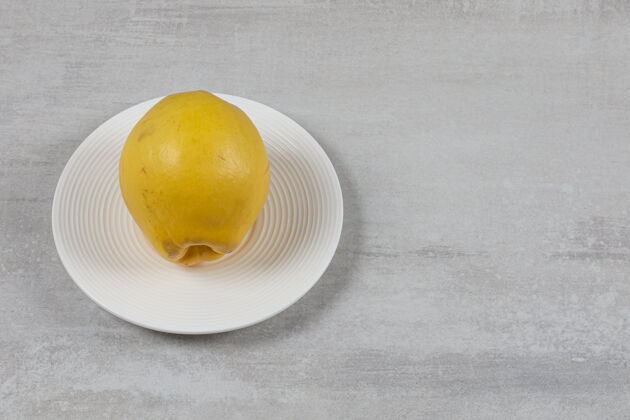 有机的在大理石表面的盘子上放一个柠檬生的美味的可口