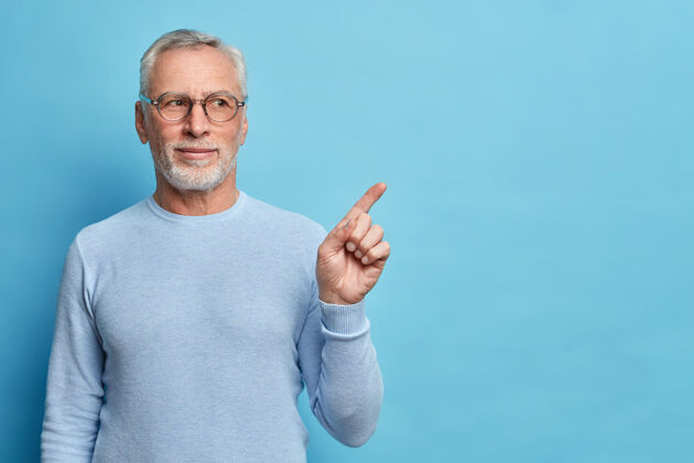 指标一位满脸满足的留着灰白胡子的欧洲老人的摄影棚镜头给人推荐 建议你把这幅广告用在蓝色墙上的休闲套头衫上外观胡须眼镜