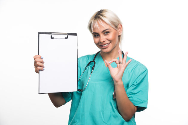 听诊器女医生拿着剪贴板在白色表面做ok手势工作女士制服