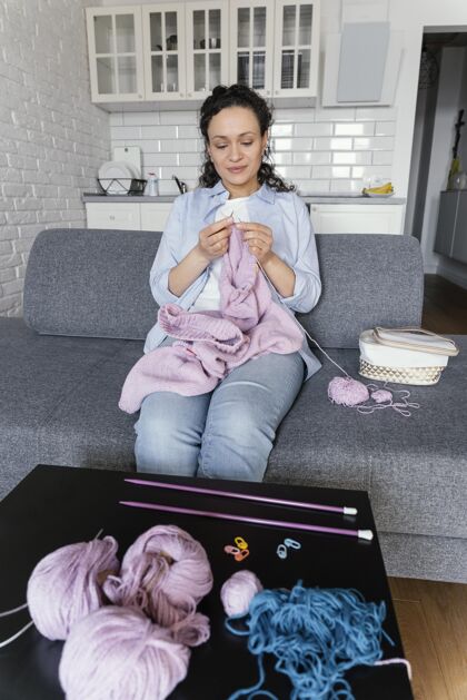 生活方式中等身材的女人在沙发上编织创意编织女人