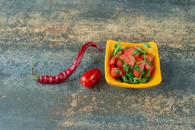 沙拉黄色盘子里的美味沙拉 大理石背景上有胡椒和西红柿美味西红柿可口