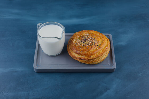 面包房一盘美味的黑籽糕点和一杯牛奶放在蓝色的表面上面包面包面包皮