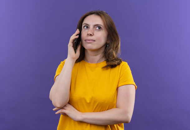 女人体贴的年轻随意的女人在隔离的紫色墙壁上讲电话 有复印空间想电话随便