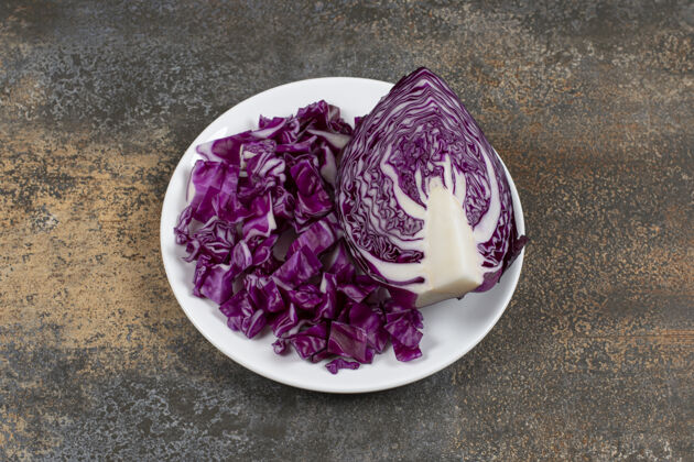 蔬菜半片红心菜旁边切碎的白菜 放在盘子上 放在大理石表面美味新鲜健康的