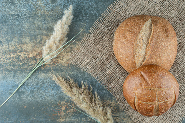 食品两个新鲜的棕色面包和麻布上的小麦面包糕点小面包