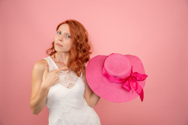 旅行粉红色墙上戴着粉红色帽子的年轻女性的正面图肖像年轻女性时尚